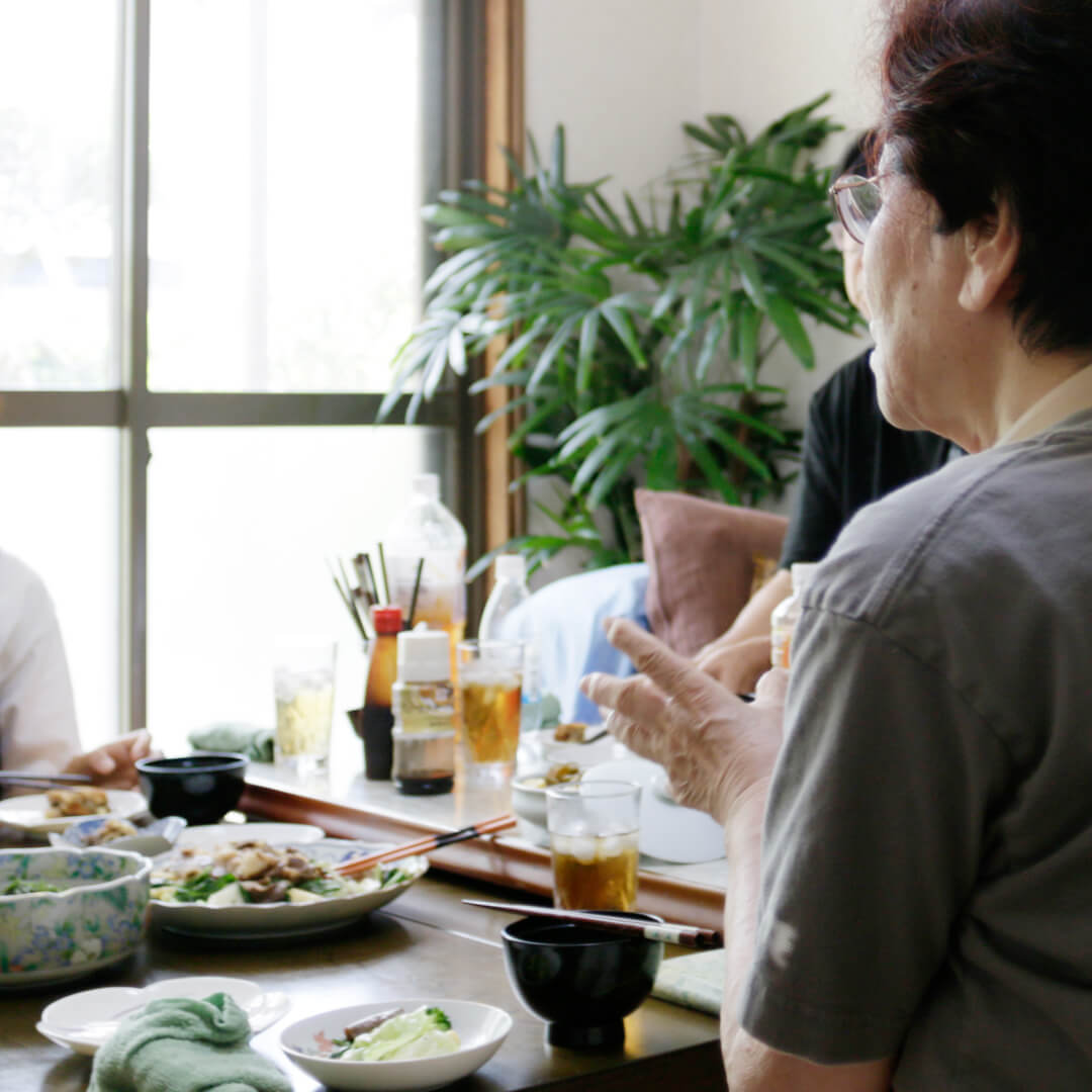 お孫さんと談笑しながら食事を楽しむお母さんの後ろ姿